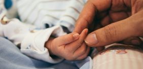 Persoon houdt handje van baby vast