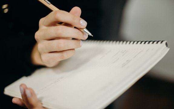 Iemand schrijft in een notitieboek