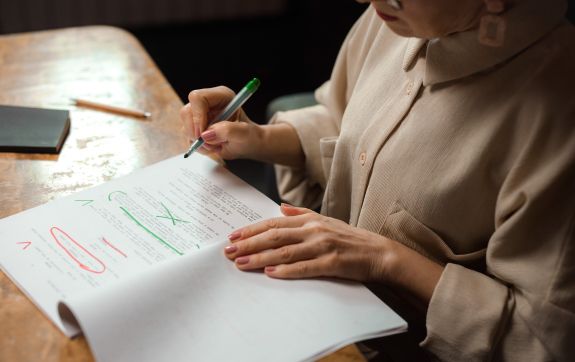 Vrouw redigeert een manuscript met groene en rode pennen