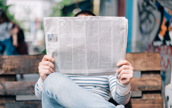 een man die op de bank een krant leest