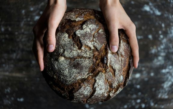 Handen omklemmen een rond brood