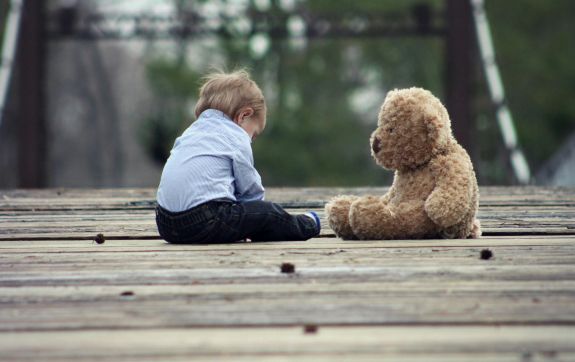 Kind en een knuffel op een brug