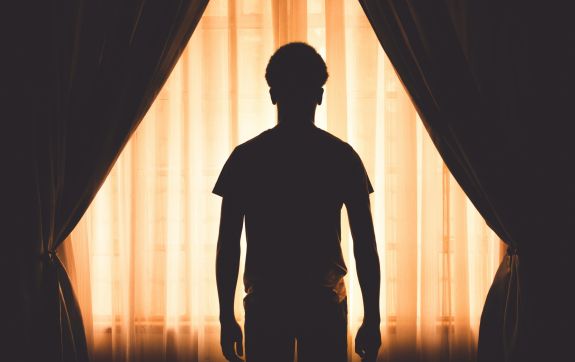 Silhouet van man voor raam met gordijnen