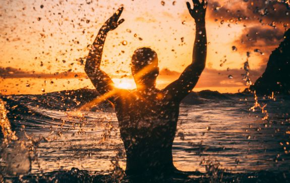 Jongen in de zee met zonsondergang