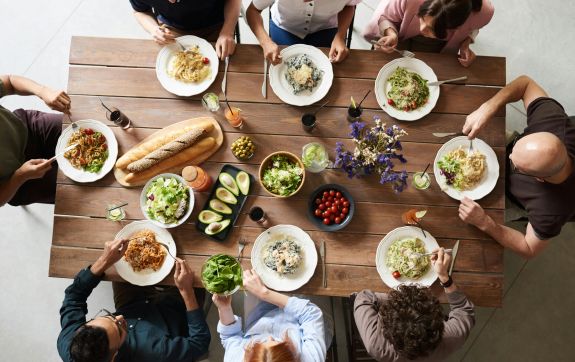 Groep mensen zitten samen aan salade en brood