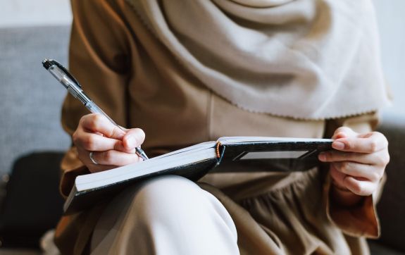 persoon aan het schrijven in een notitieboek