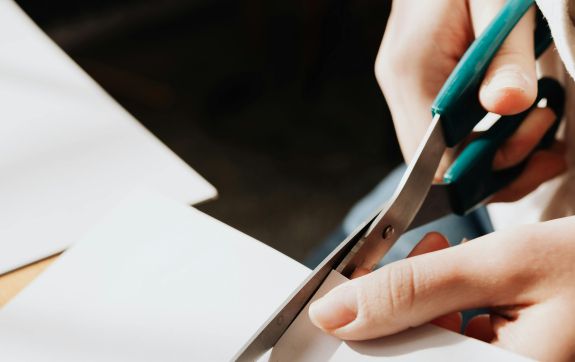 Persoon knipt met een schaar in wit papier