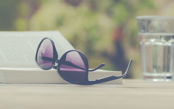 zonnebril op boek met glas water ernaast