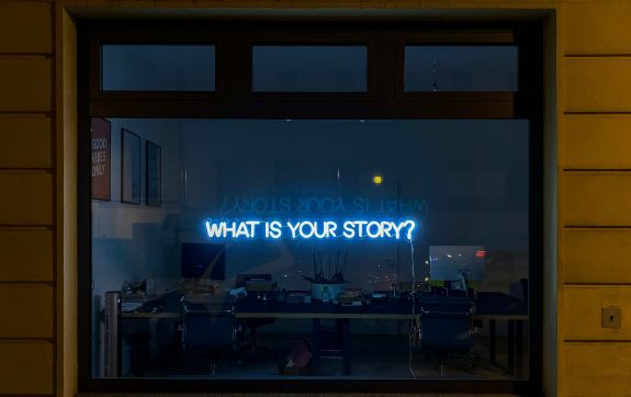 Neon letters 'what is your story' hangt in een raam