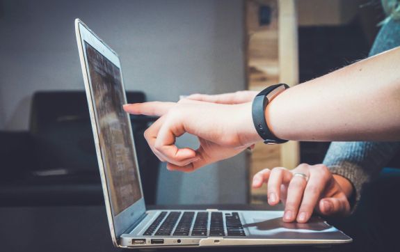 Iemand wijst op laptopscherm om feedback te geven