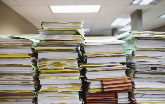 Stapels met mappen vol papier op een bureau