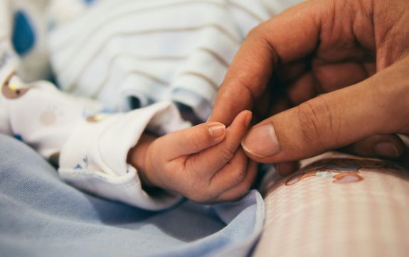 Persoon houdt handje van baby vast